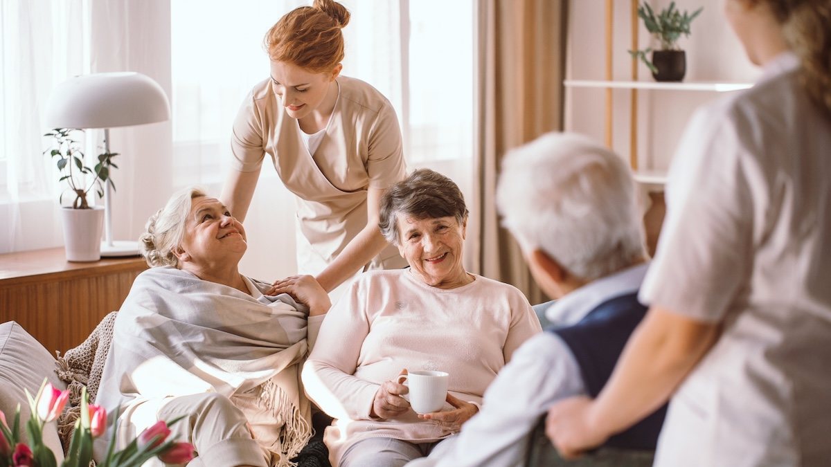 Carers and residents talking together in a care home lounge