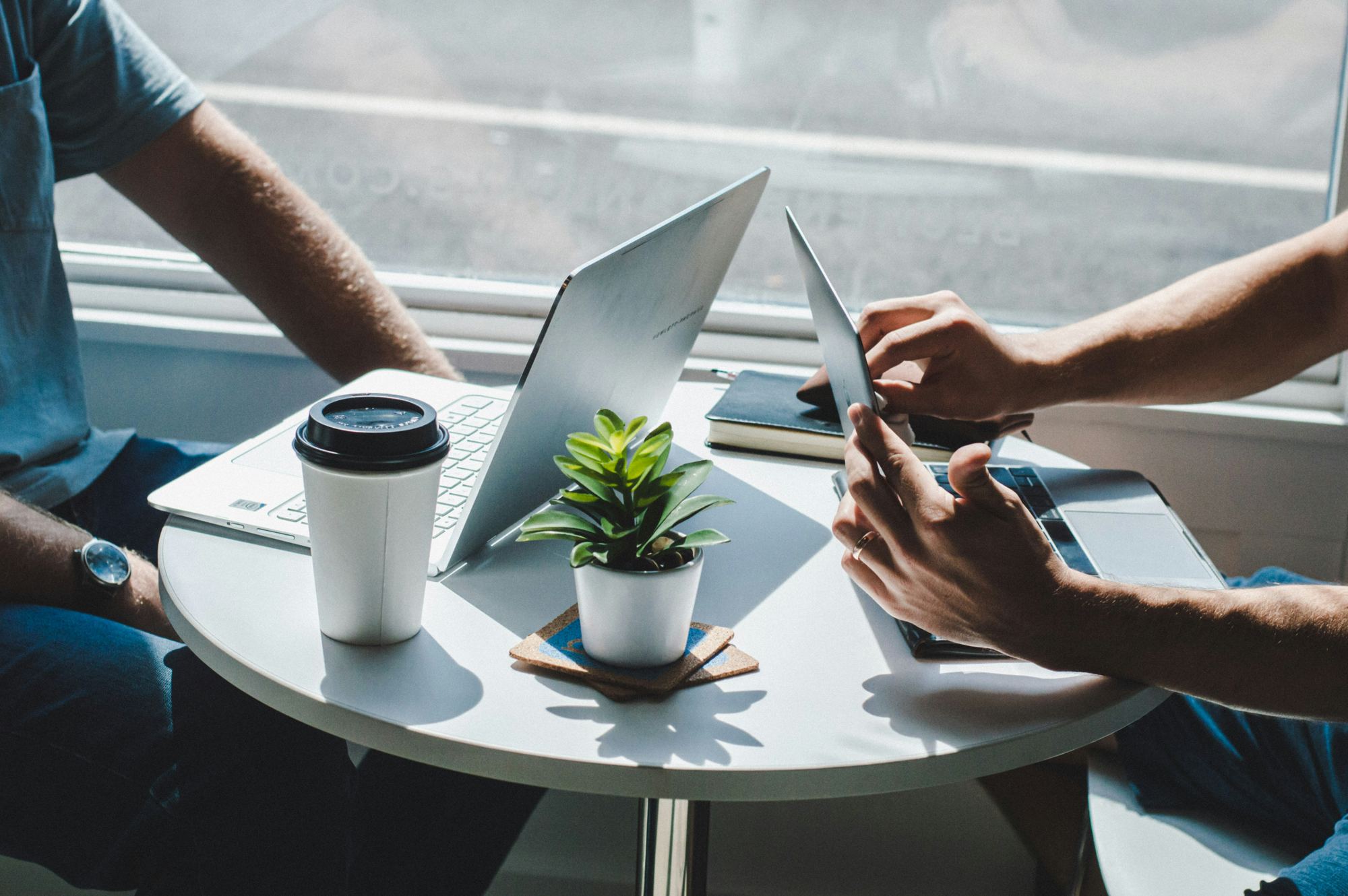 Two people working on laptops at a small meeting table