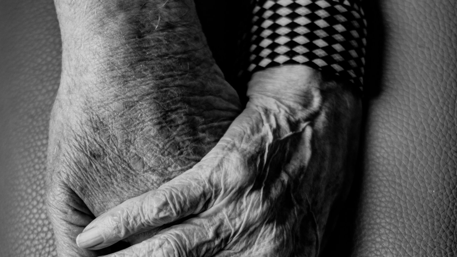 An older person's hands resting together, in black and white