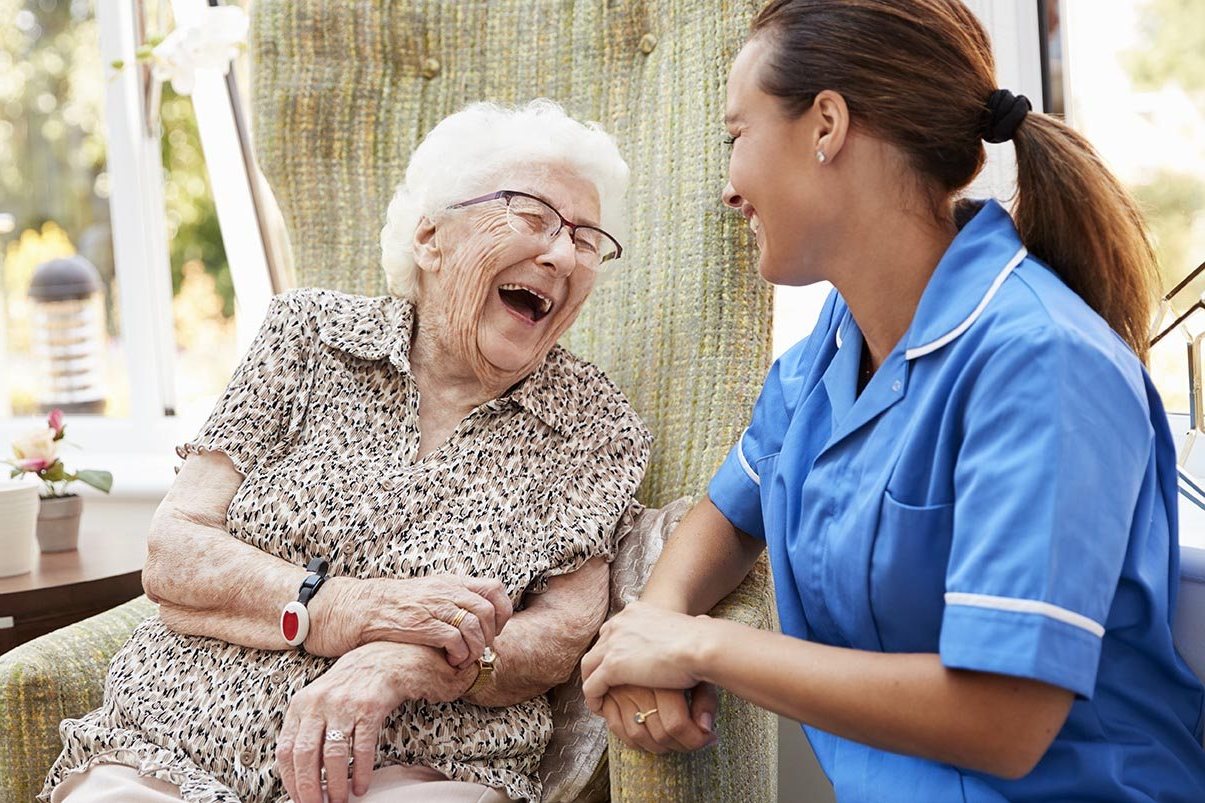 An older woman smiling in a care home lounge
